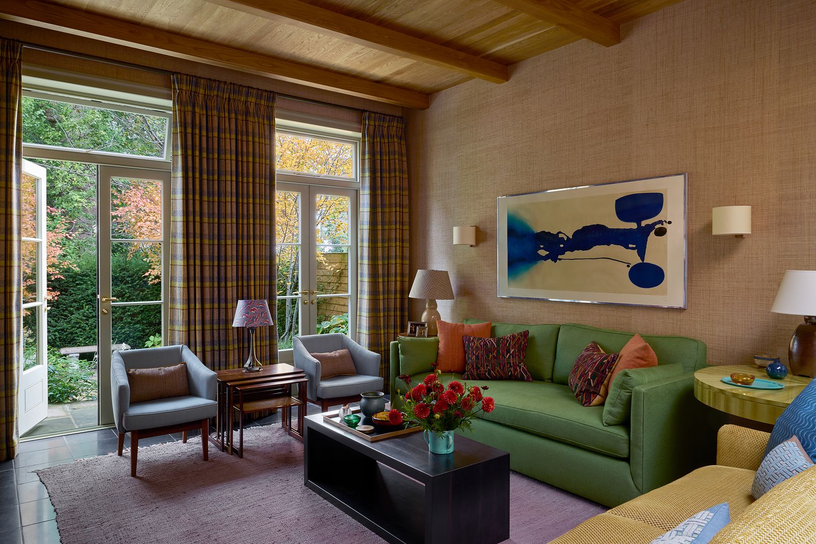 A green sofa covered in ‘Toile Sauvageonne from Charles Burger sits below a Victor Pasmore print. The curtains are in a...