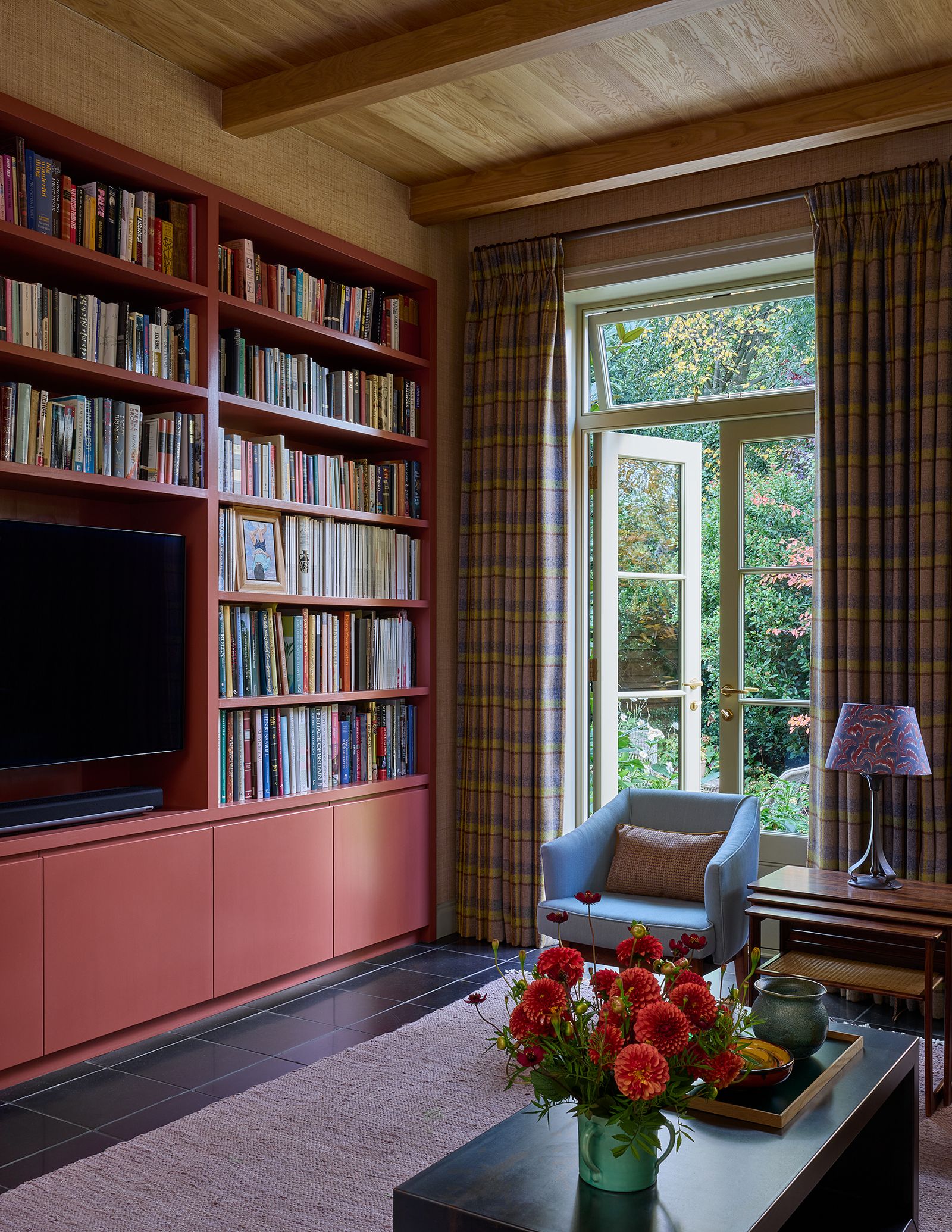 Brandon designed the red bookcase and TV cabinet which is set into the wall. The blue chairs are covered in ‘Tartarin...