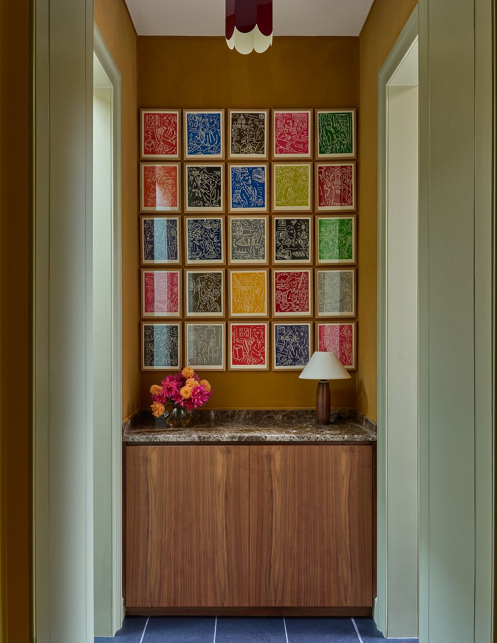 A set of woodblock prints by Adrian Wiszniewski hang above a walnut cabinet in the corridor.