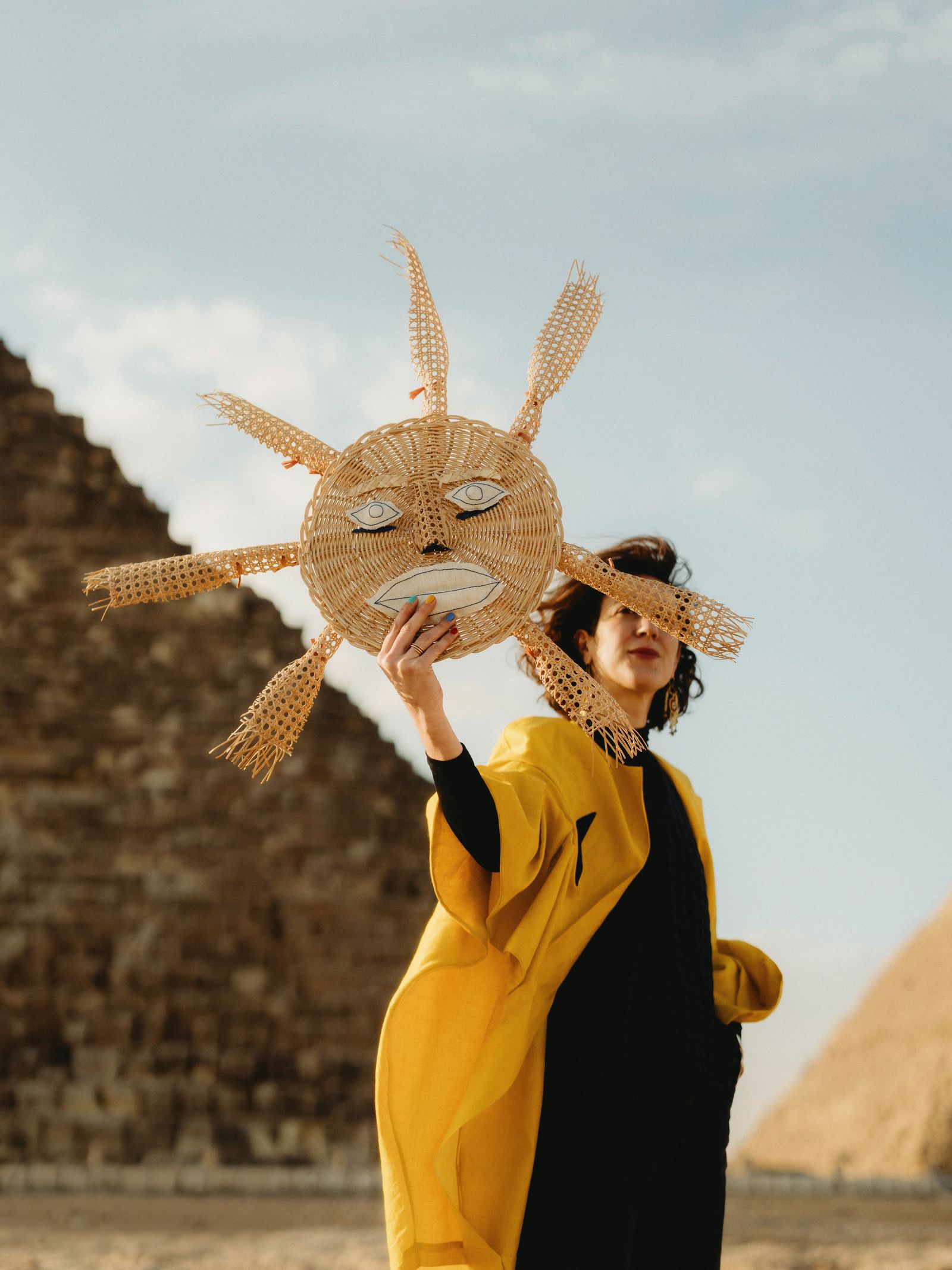 Cruz Wyndham creative director of Anūt Cairo at the Giza pyramids with a mask made for one of the lifestyle brands...