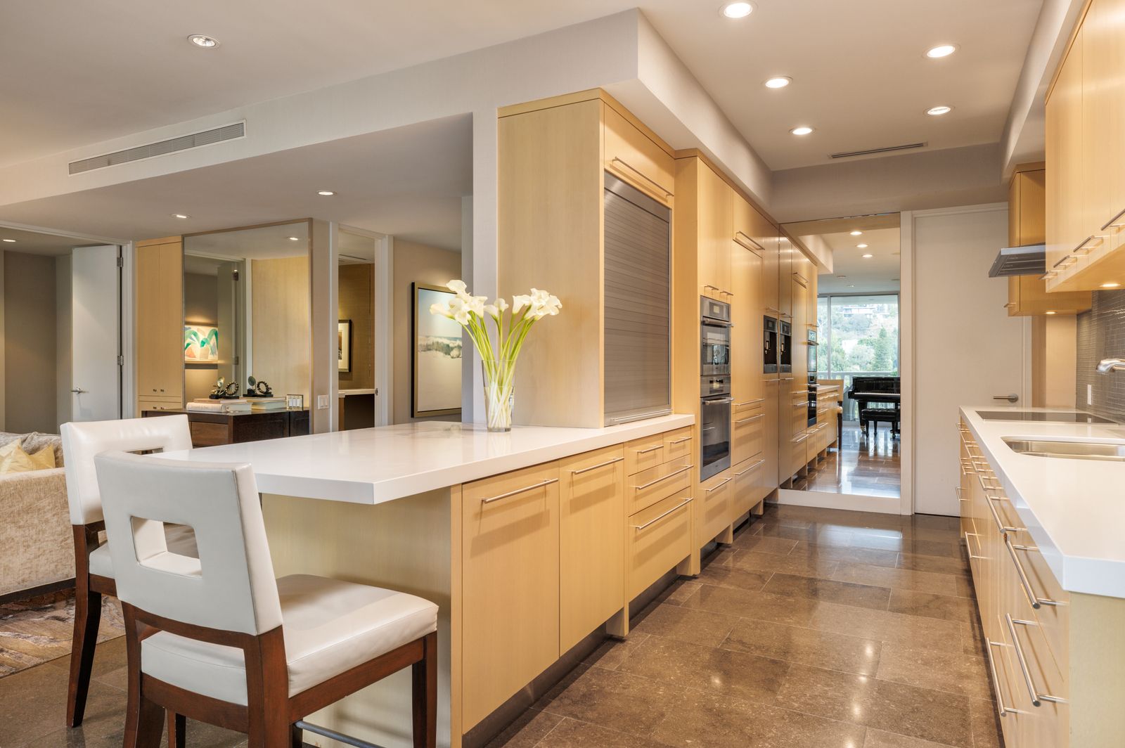 kitchen with blonde wood white countertop white barstools