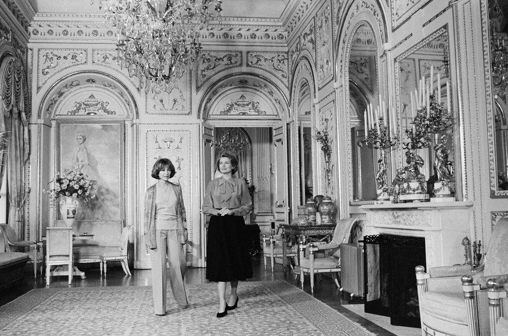 blackandwhite photo of Lee Grant left and Grace Kelly walking through the Mirror Gallery an ornate room in the Princes...
