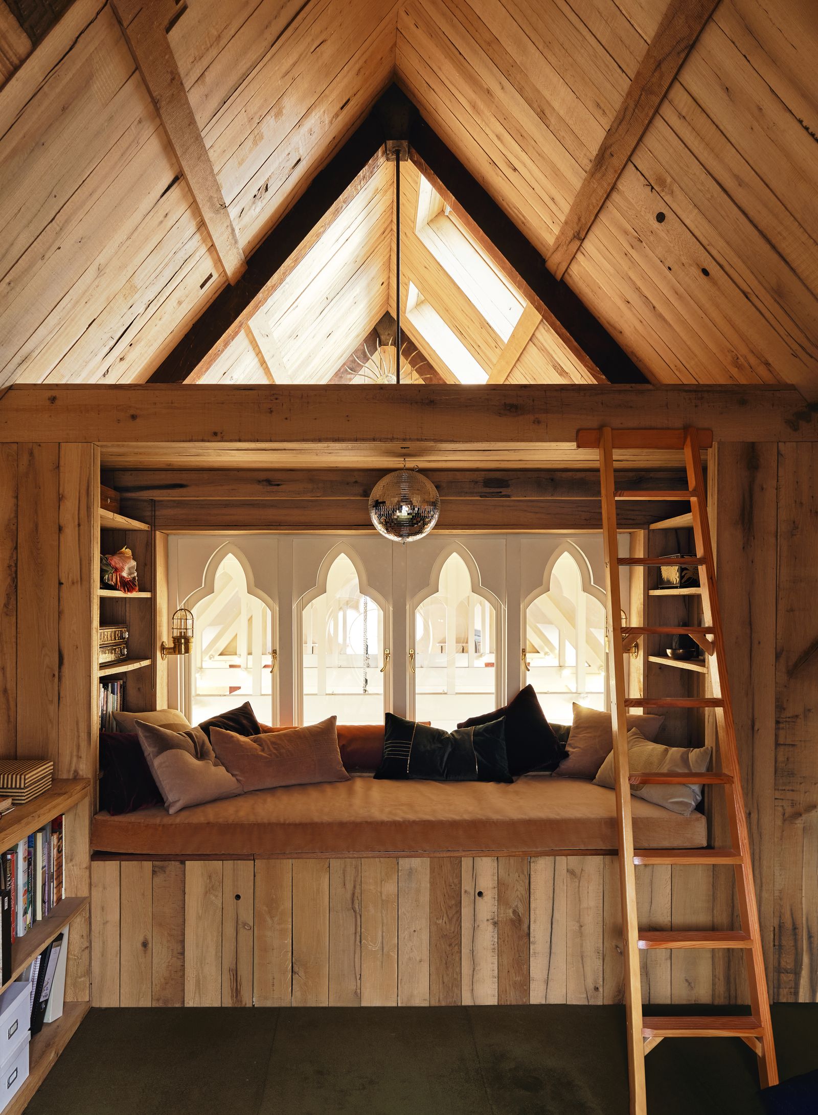 A builtin seating area in antique oak featuring Lucys handdyed velvet cushions conceals a bath below an iroko top.