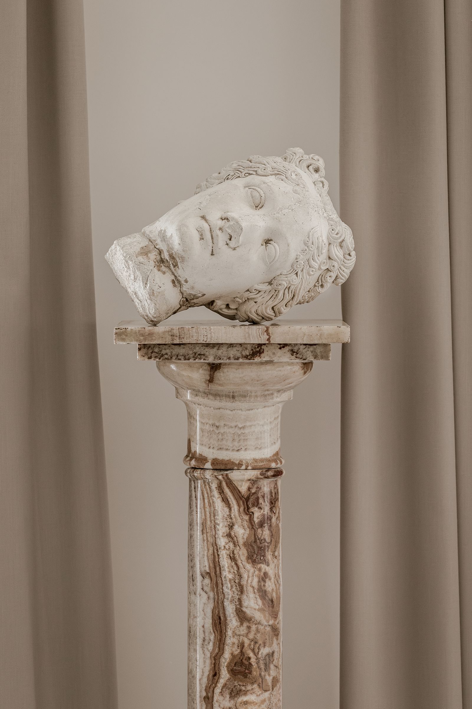 A marble bust of Venus sits atop a marble base.
