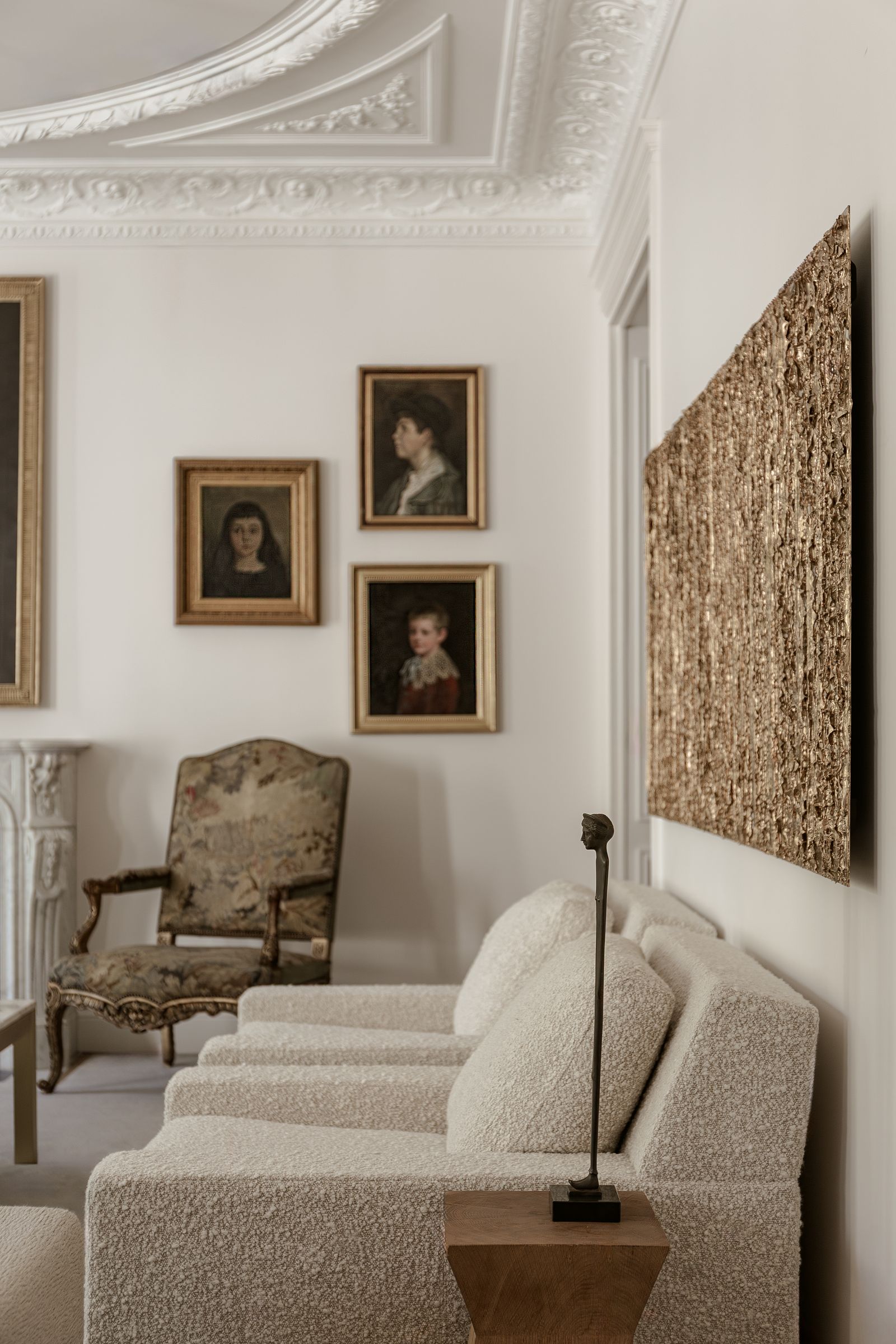 living room with boucle armchairs white walls with golden framed art and bronze sculpture