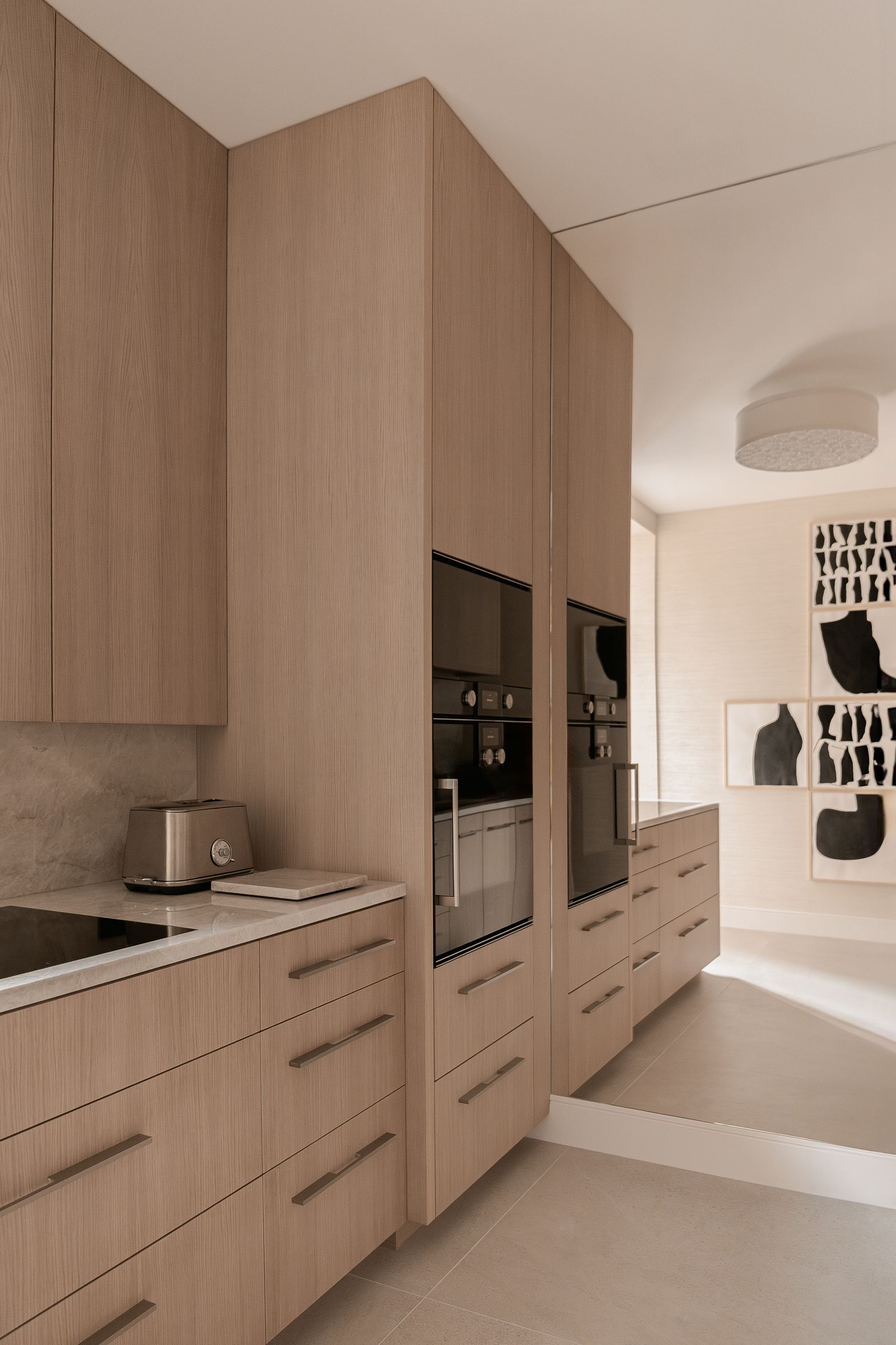 modern kitchen with a sleek cabinet design in light wood and white marble